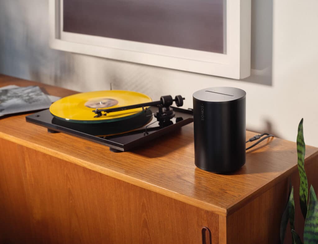 the new sonos products: sonos era 100 in black on wooden furniture next to record player